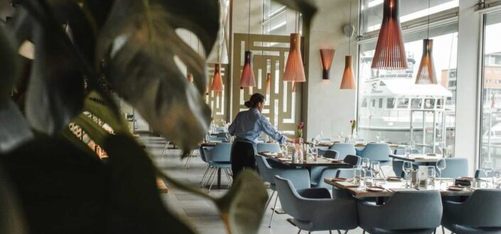Woman Arranging Table and Chairs in Restaurant